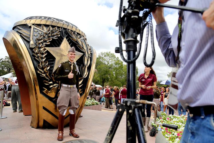 Corps member standing in front of the Aggie Ring.