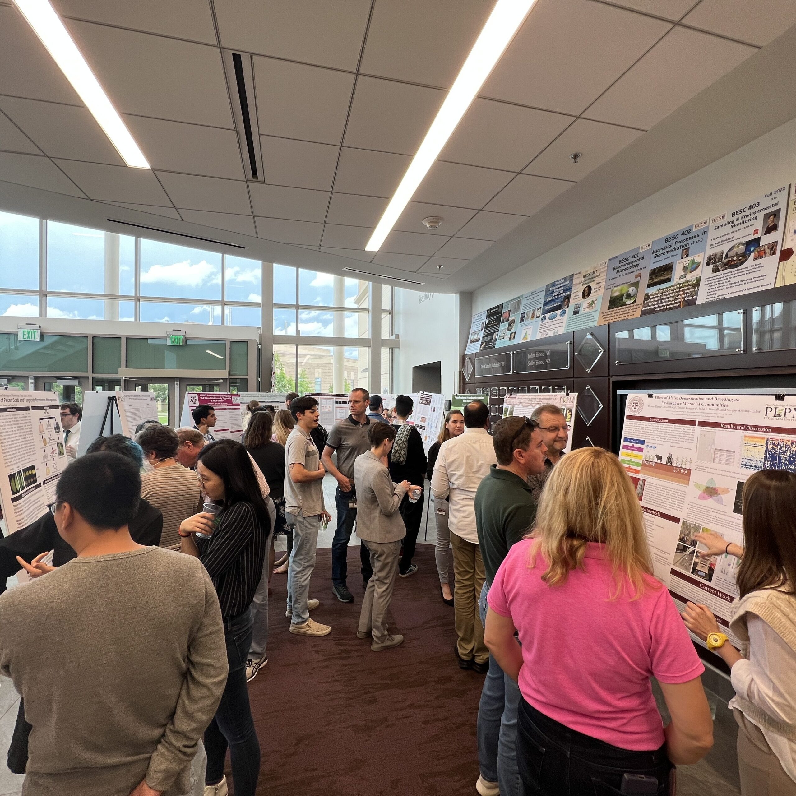 group of people around a room looking at presentation boards